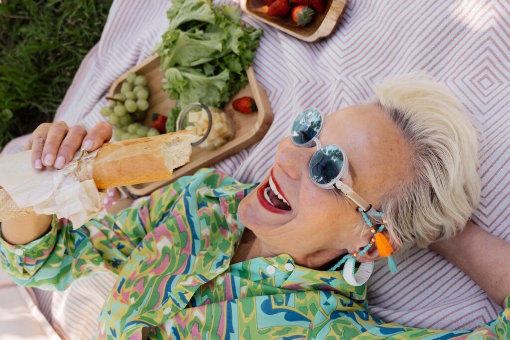 Woman having a picnic with a sandwich and a big smile after taking one of the best delta 8 strains for spring. 