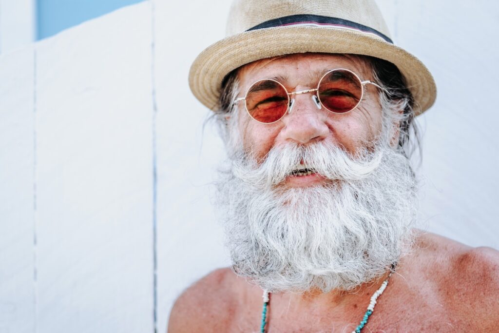 Old man with a beard smiling because he took the best cannabis strains to promote happiness. 