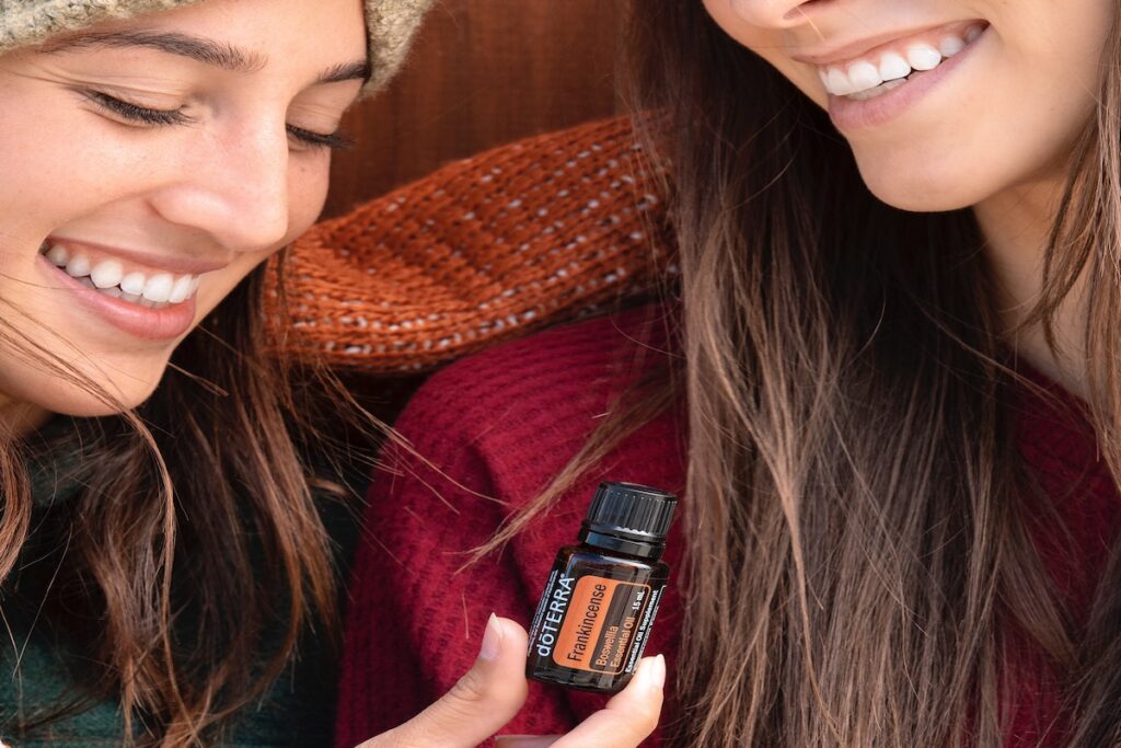 Two women holding frankincense essential oils. 