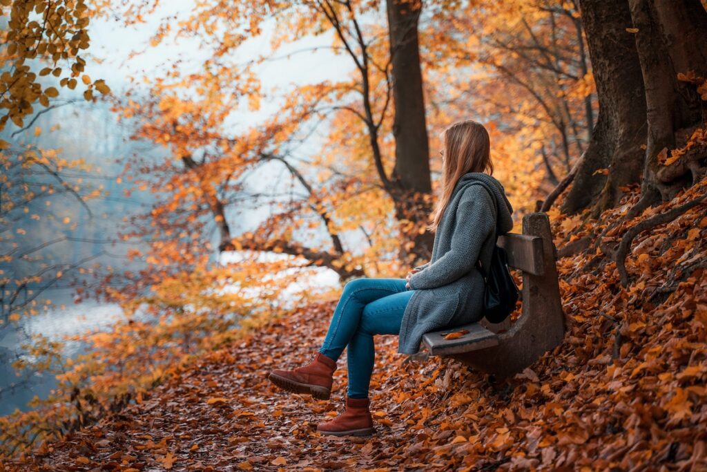 Woman sitting on a bench during the fall. 