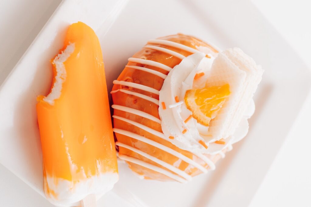 Dreamsicle popsicle next to a dreamsicle donut. 