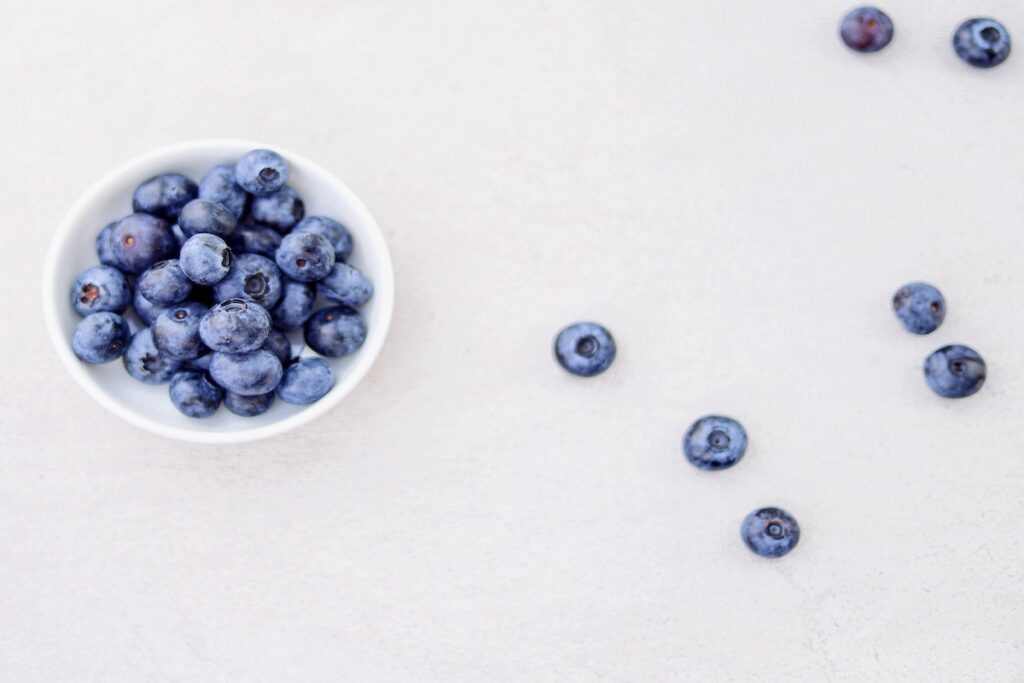 Blueberries in a bowl and on a table during National Blueberry Month.