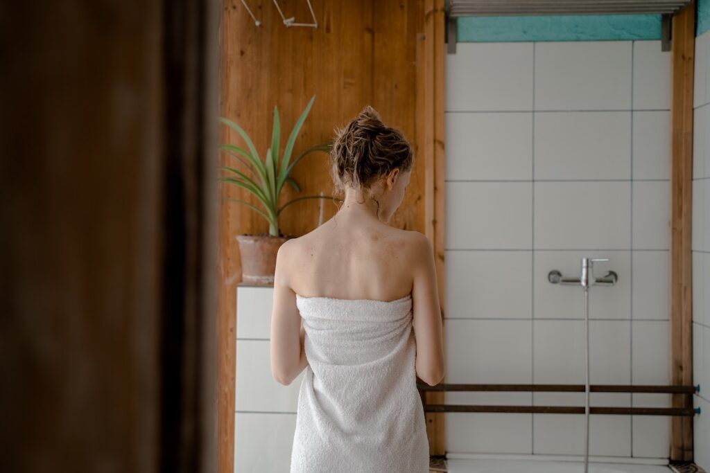 Woman standing outside of her shower before doing one of the most unique self-care ideas: the "everything" shower. 