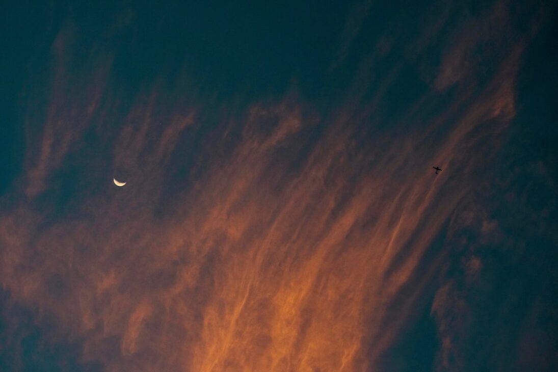 New moon in the sky with clouds over it. 