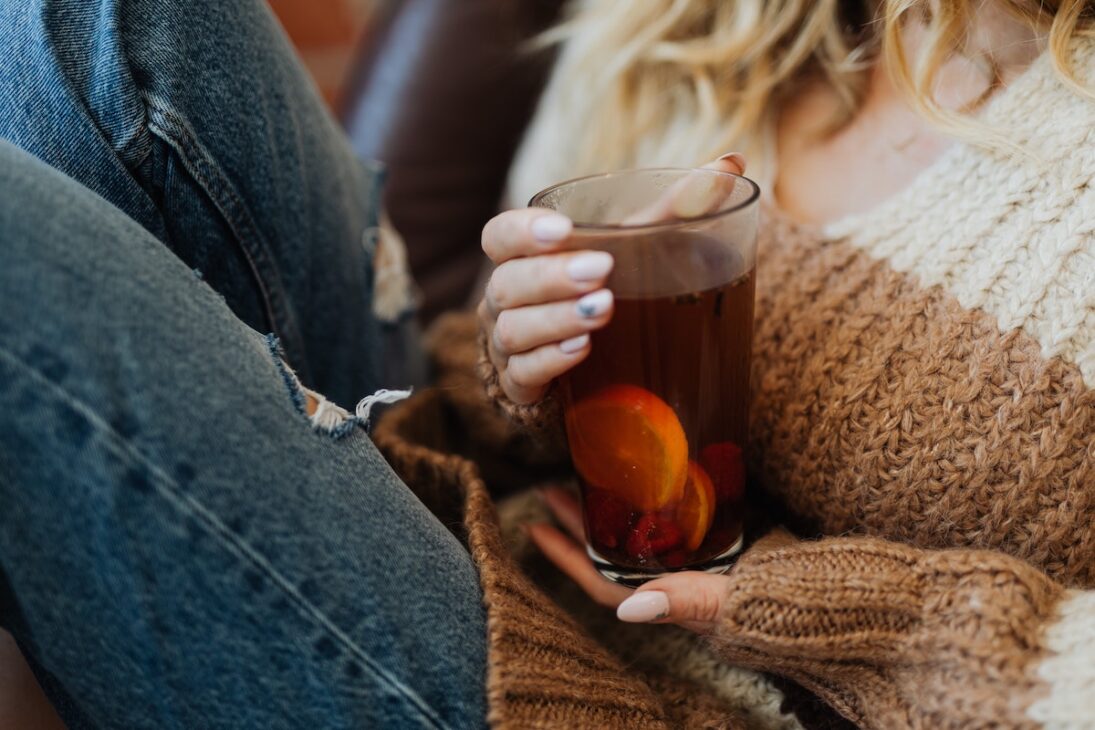 Woman in a cozy fall sweater drinking spiced cider.