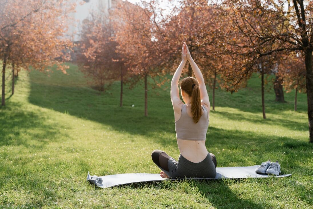 Woman practicing yoga outside during the fall to boost her mental health. 