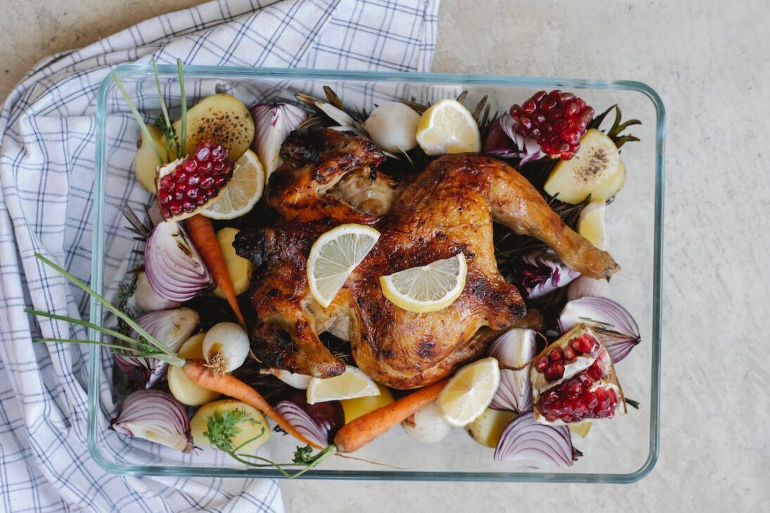 Roasted chicken with vegetables and fruit in a roast pan. 