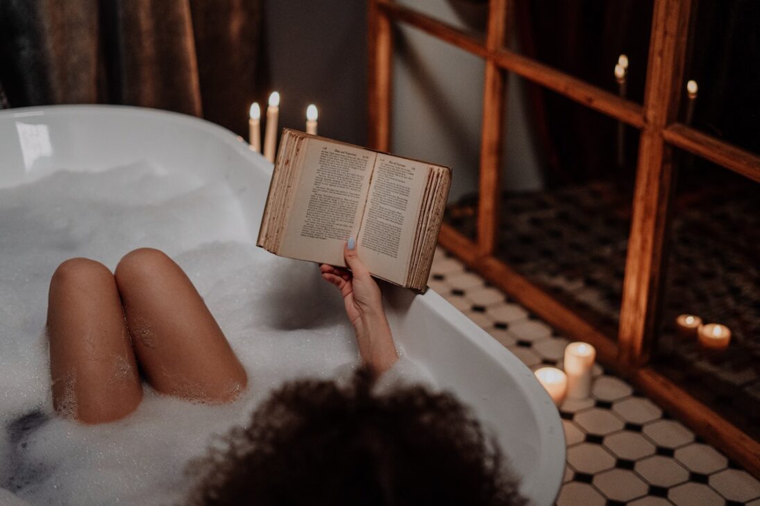 Woman reading in a bath tub. 