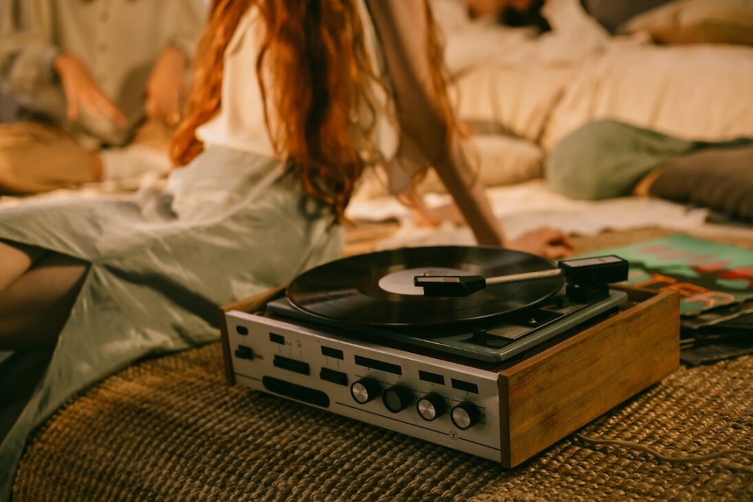 Woman sitting next to a record player while she listens to music and she's stoned. 