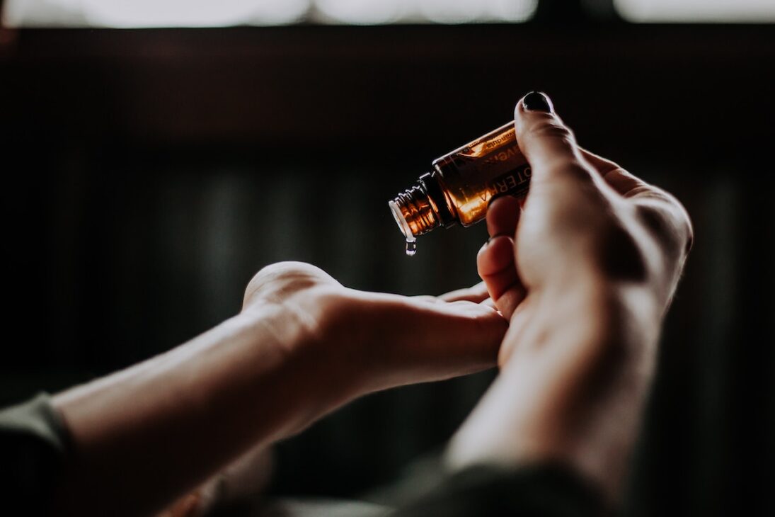 Woman pouring essential oils for travel into her hand. 