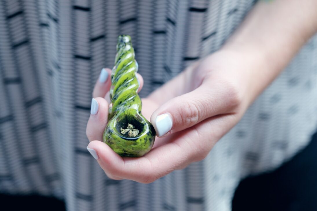 Woman with a pipe and Indica cannabis. 
