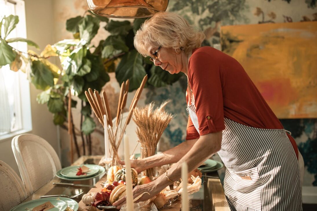 Woman setting up a Thanksgiving tablescape. 